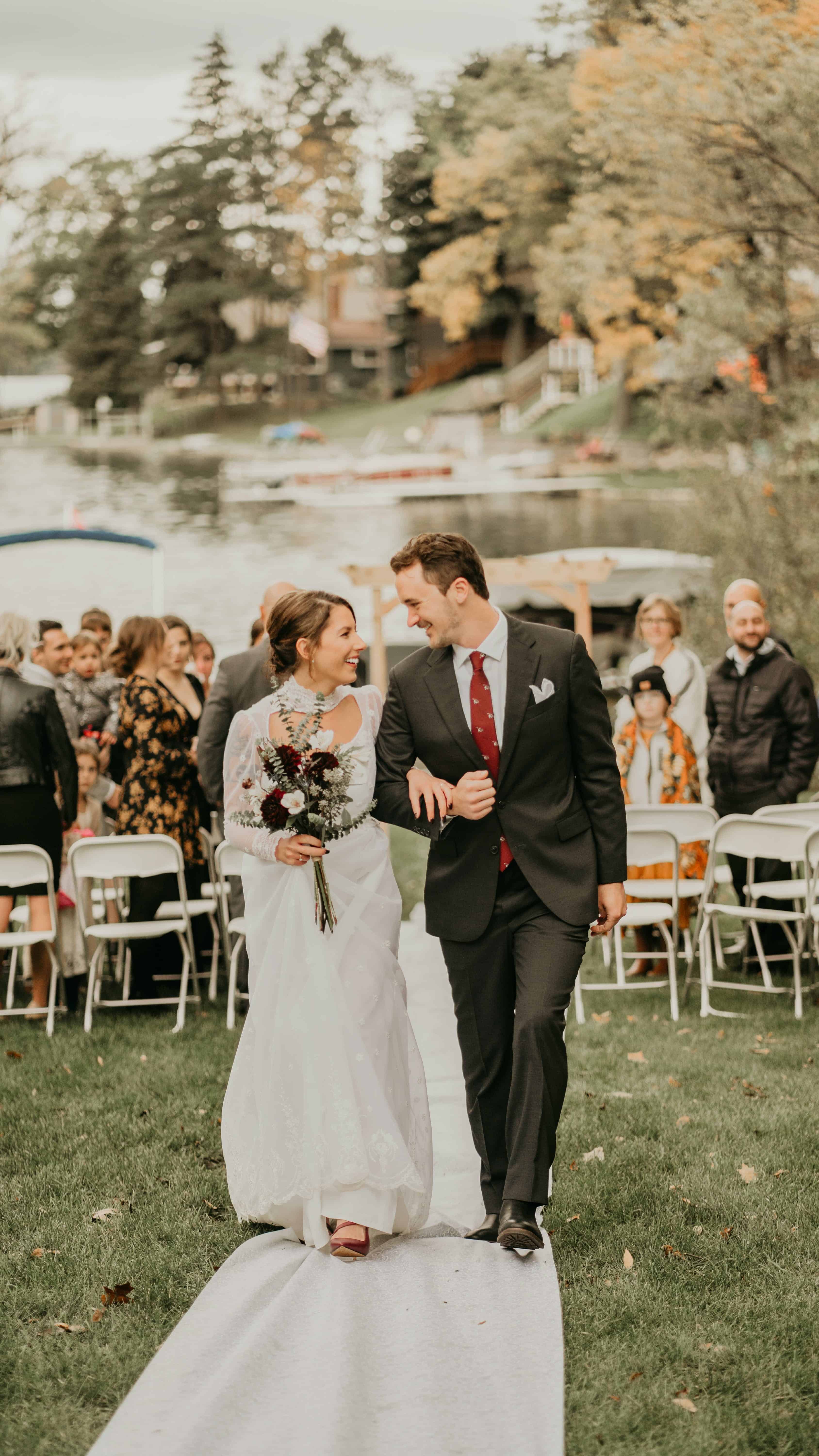 Free Wedding Photo of Couple Walking Down Aisle with Lake in Background Stock Photo