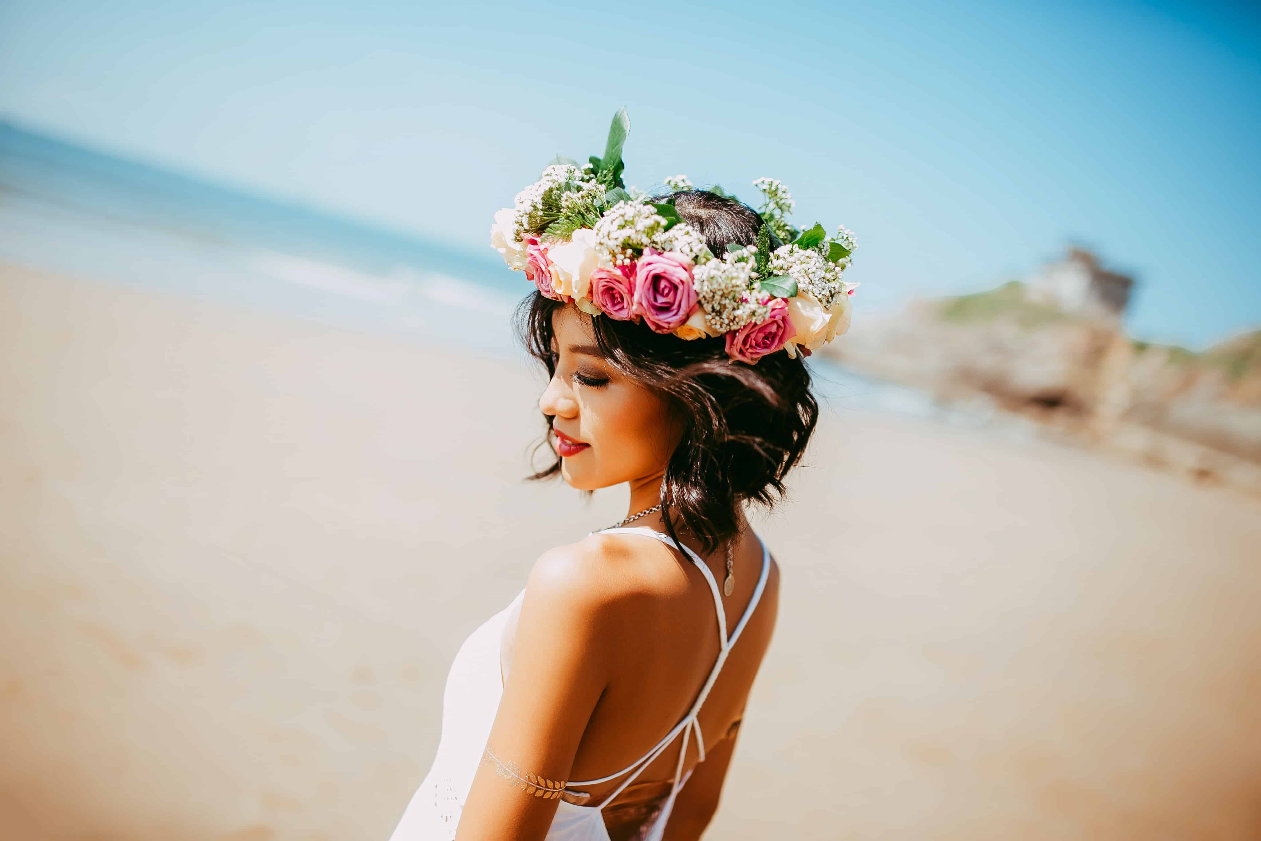 woman wearing white halter dress and floral tiara at shore during daytime