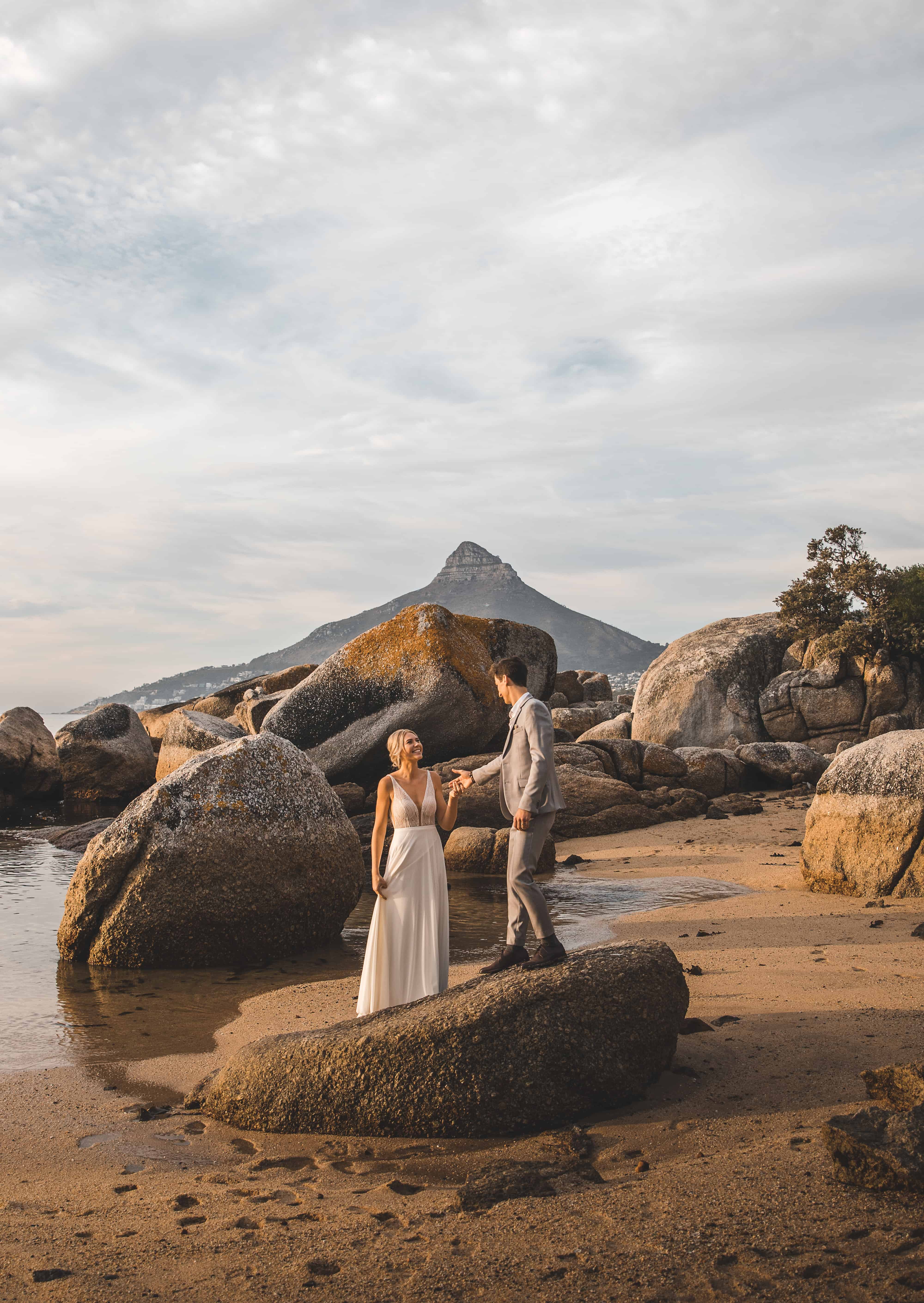 woman in white dress standing on brown rock near body of water during daytime