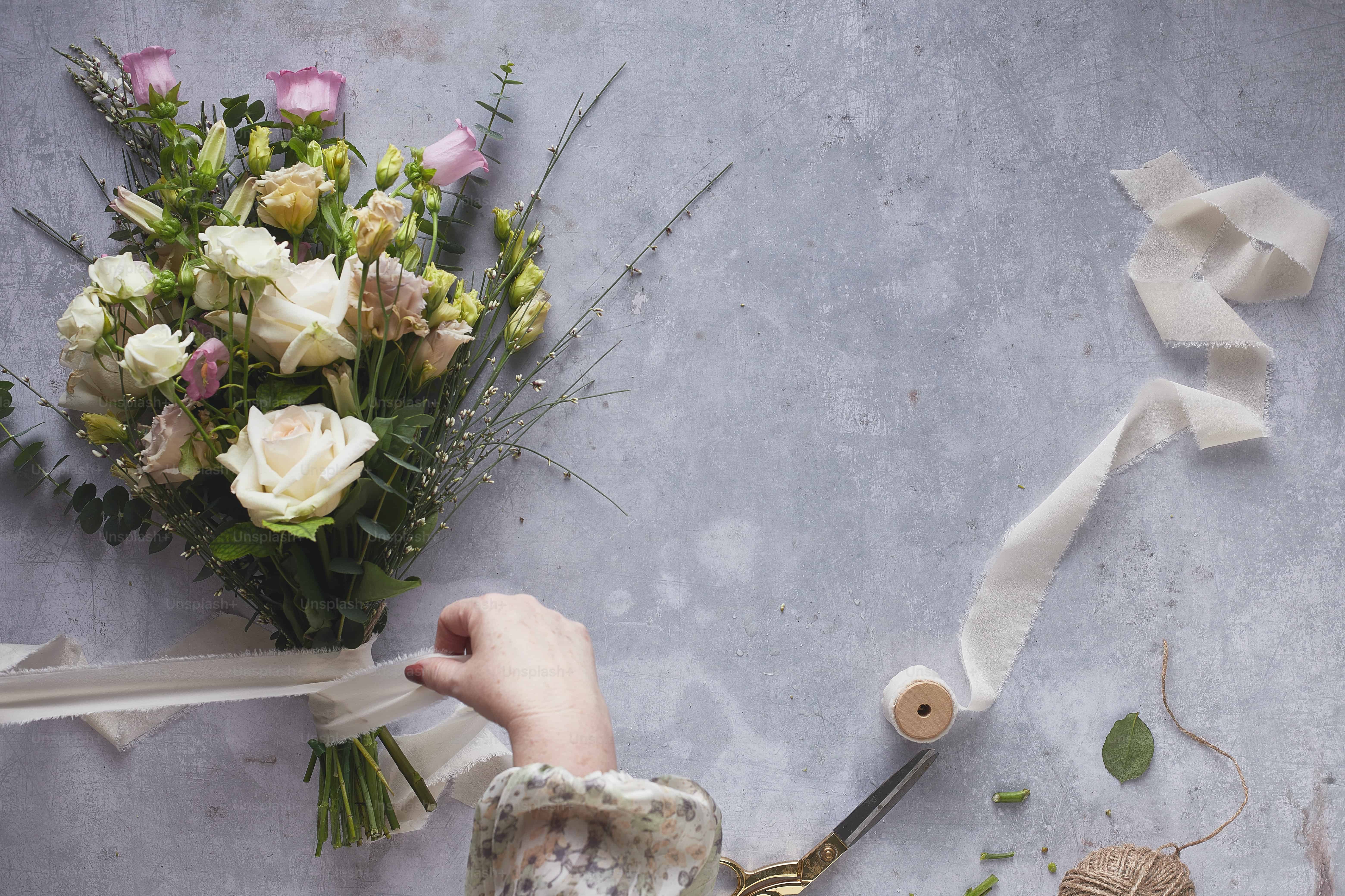 a person holding a pair of scissors next to a bouquet of flowers
